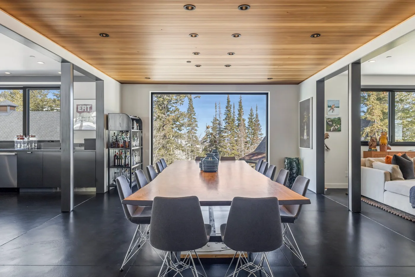 A dining area with a long table and chairs beneath a wood-paneled ceiling.