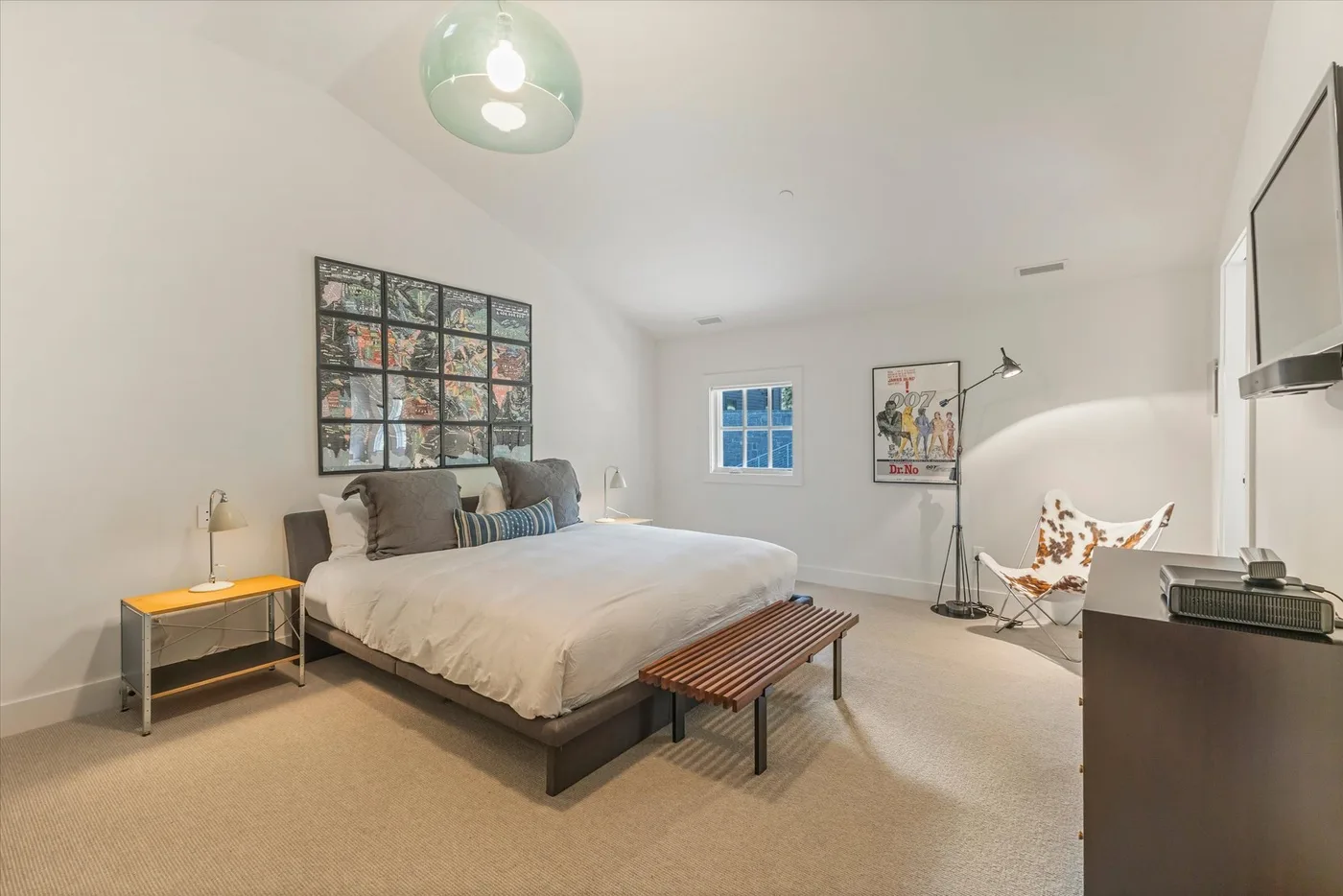 A bedroom with a large bed, a bench, and a window.
