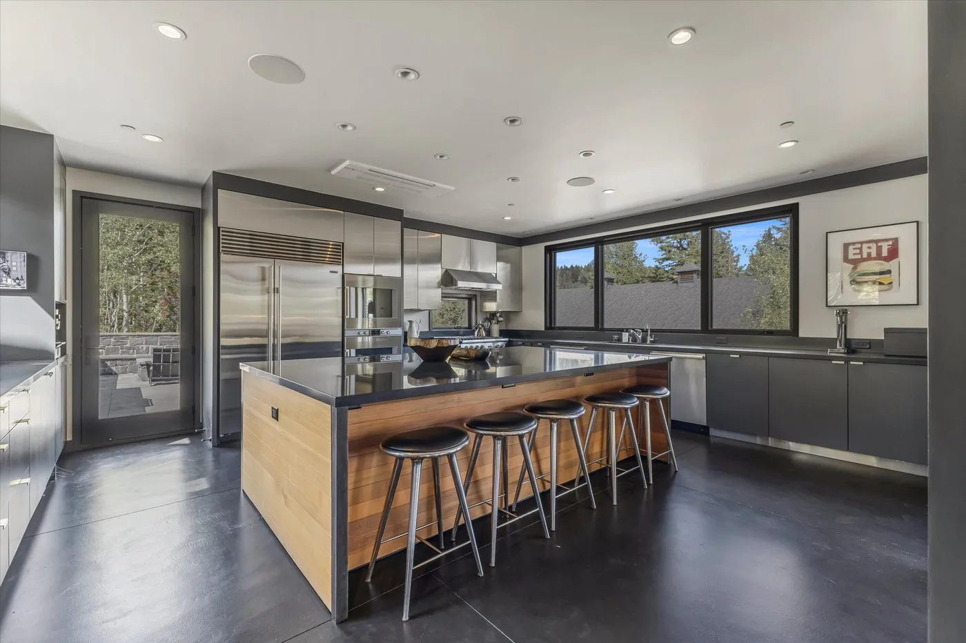 A modern kitchen with a wood-front island and metal bar stools.