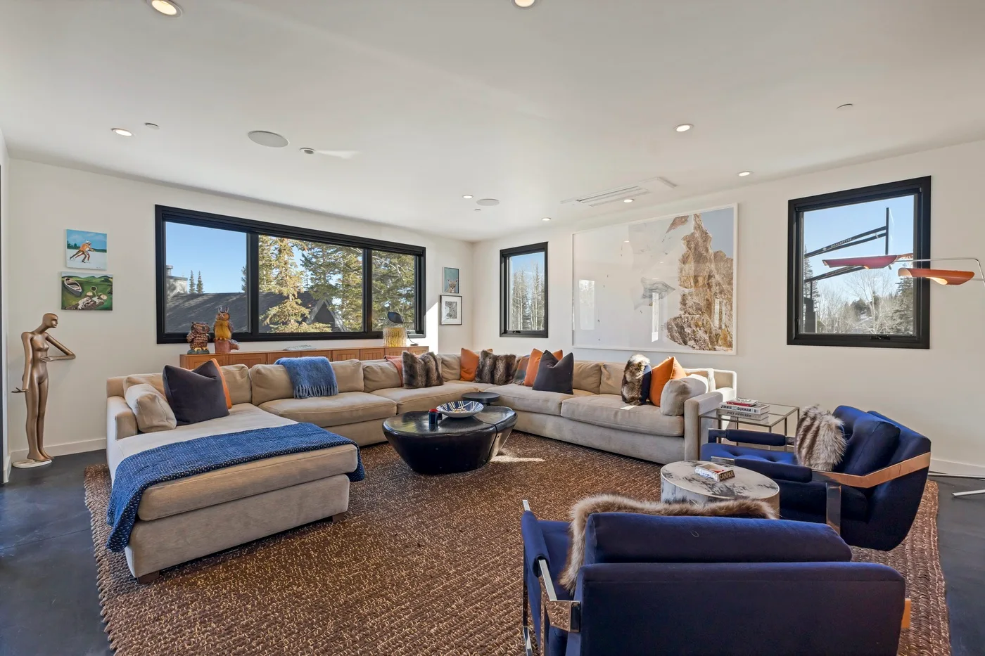 A bright living room with sectional seating, a coffee table, and large windows.
