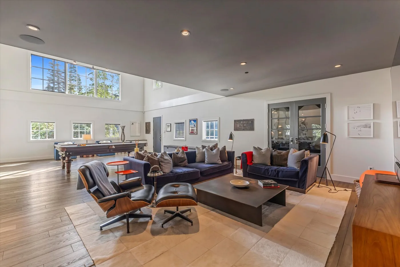 A spacious living room with seating around a low coffee table and a pool table behind it.