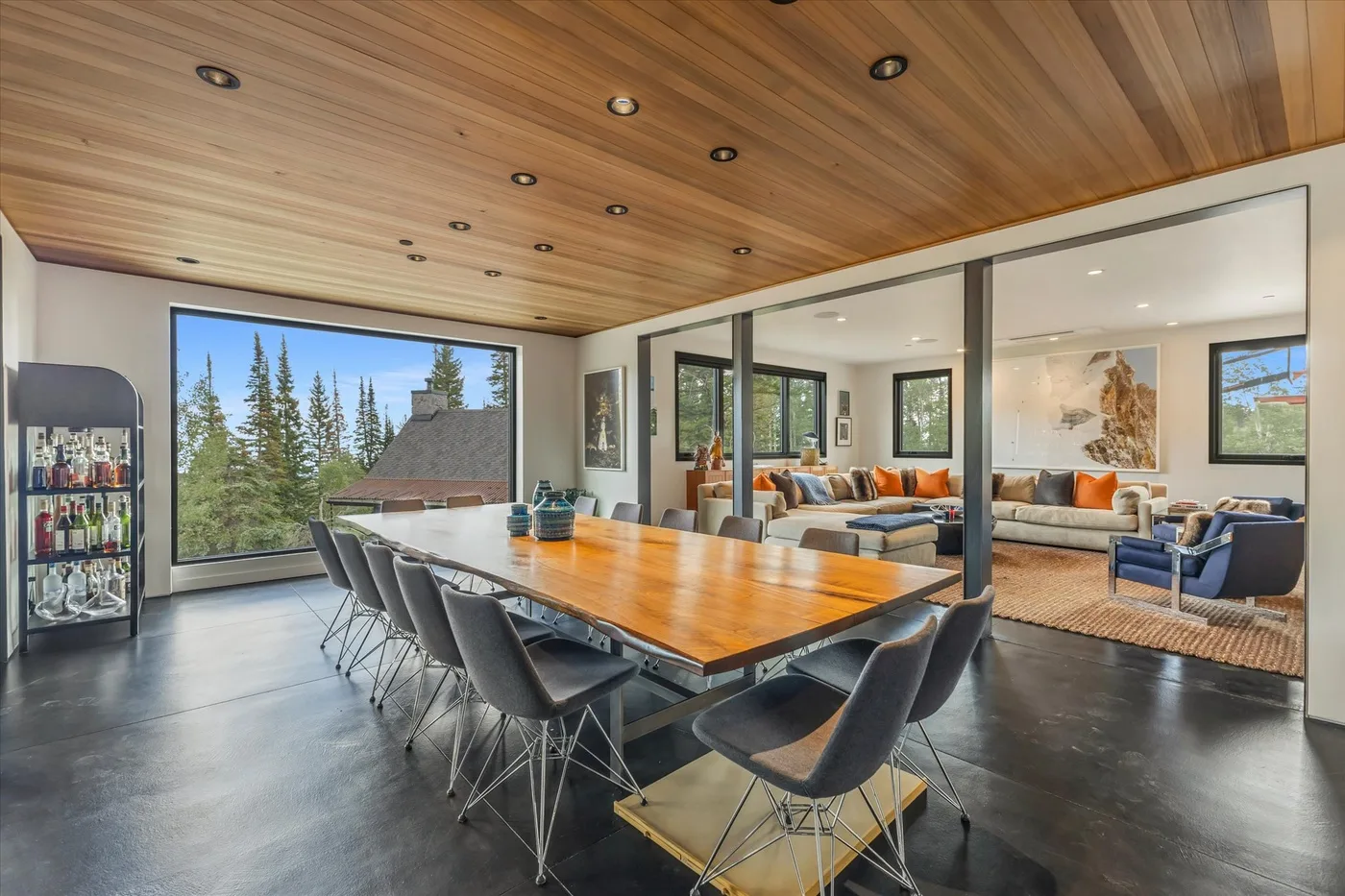 A dining area with a long table and chairs, opening onto a living room.