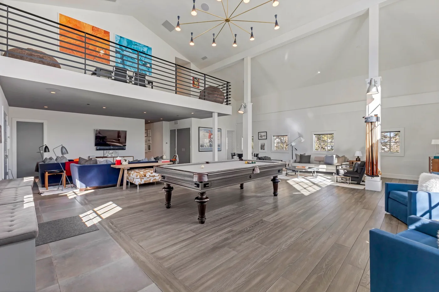 A spacious loft living area features a pool table and seating beneath an upper-level railing.