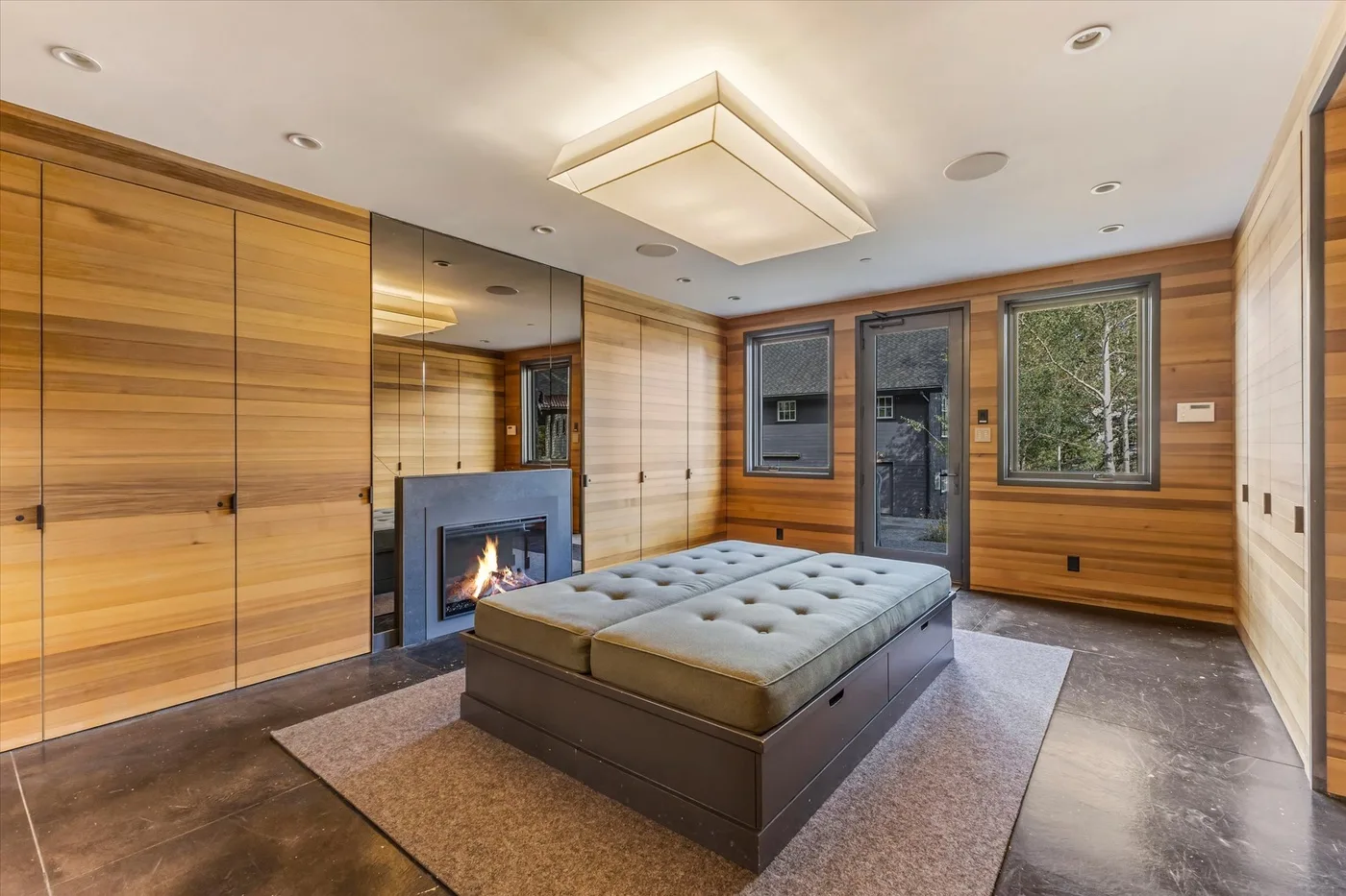 A wood-paneled bedroom with a large bed and a fireplace.