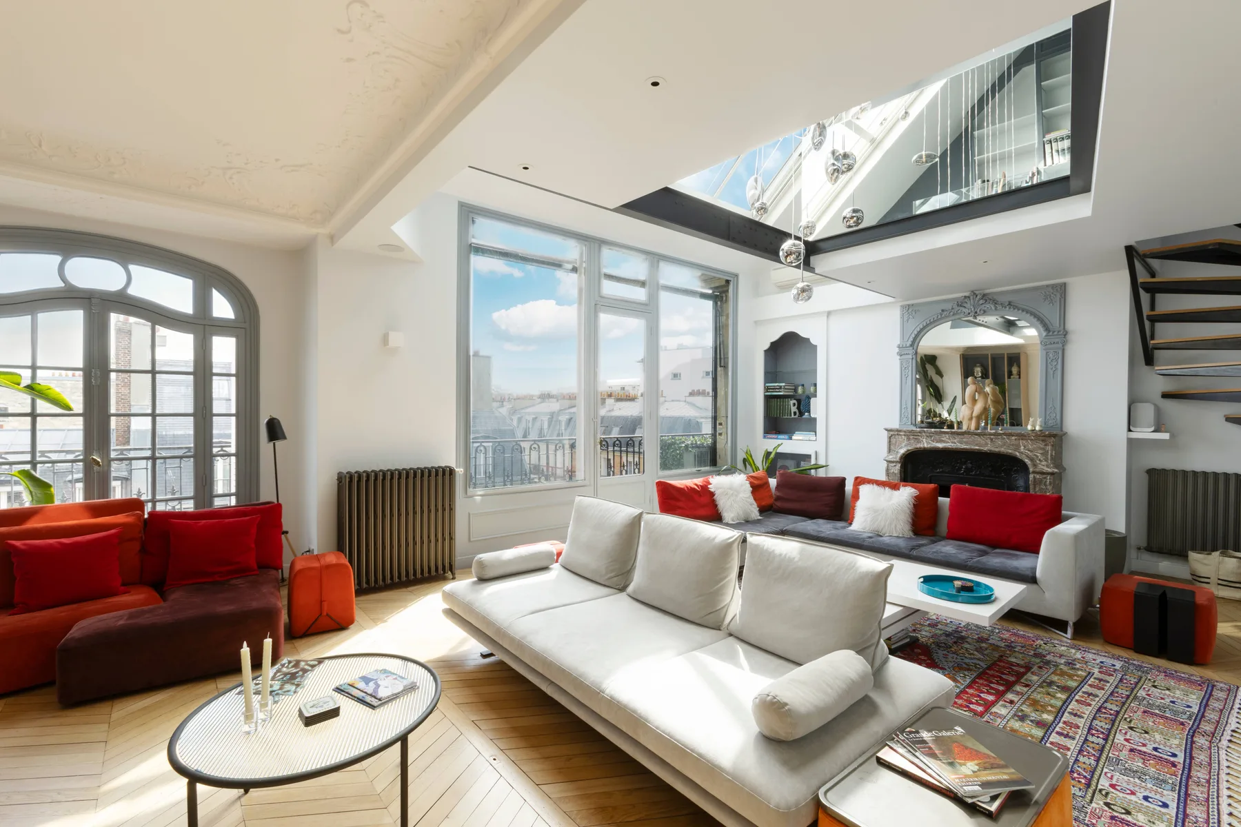Bright living room with white seating, red cushions, and large windows.