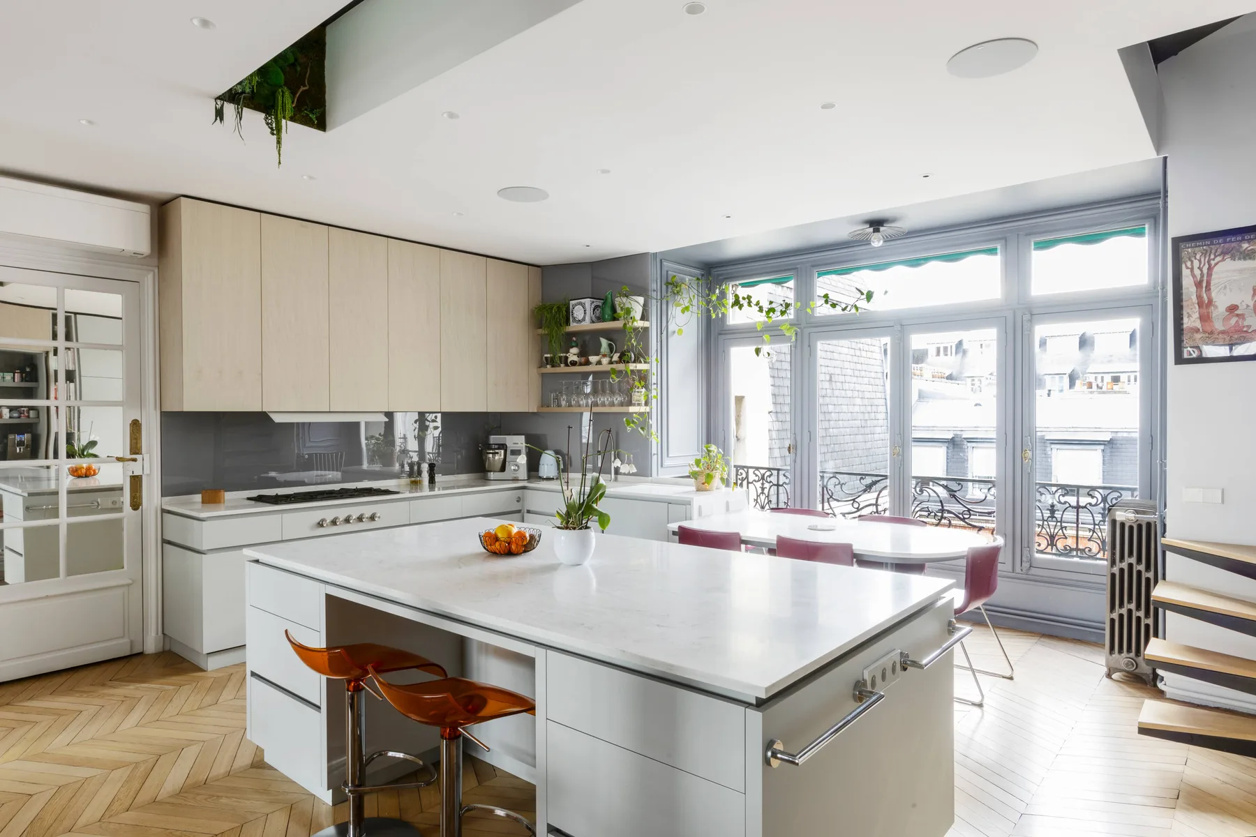 A bright modern kitchen with a large island and windows overlooking a balcony.
