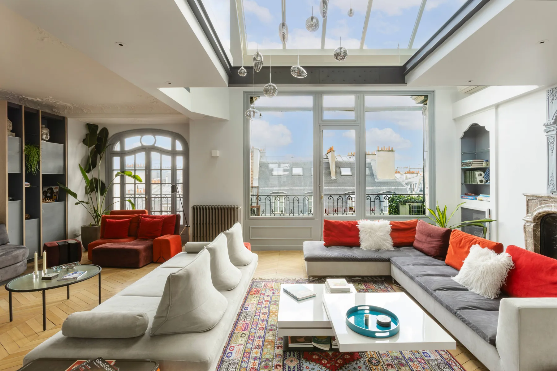 A bright living room with seating arranged around a coffee table beneath a skylight.