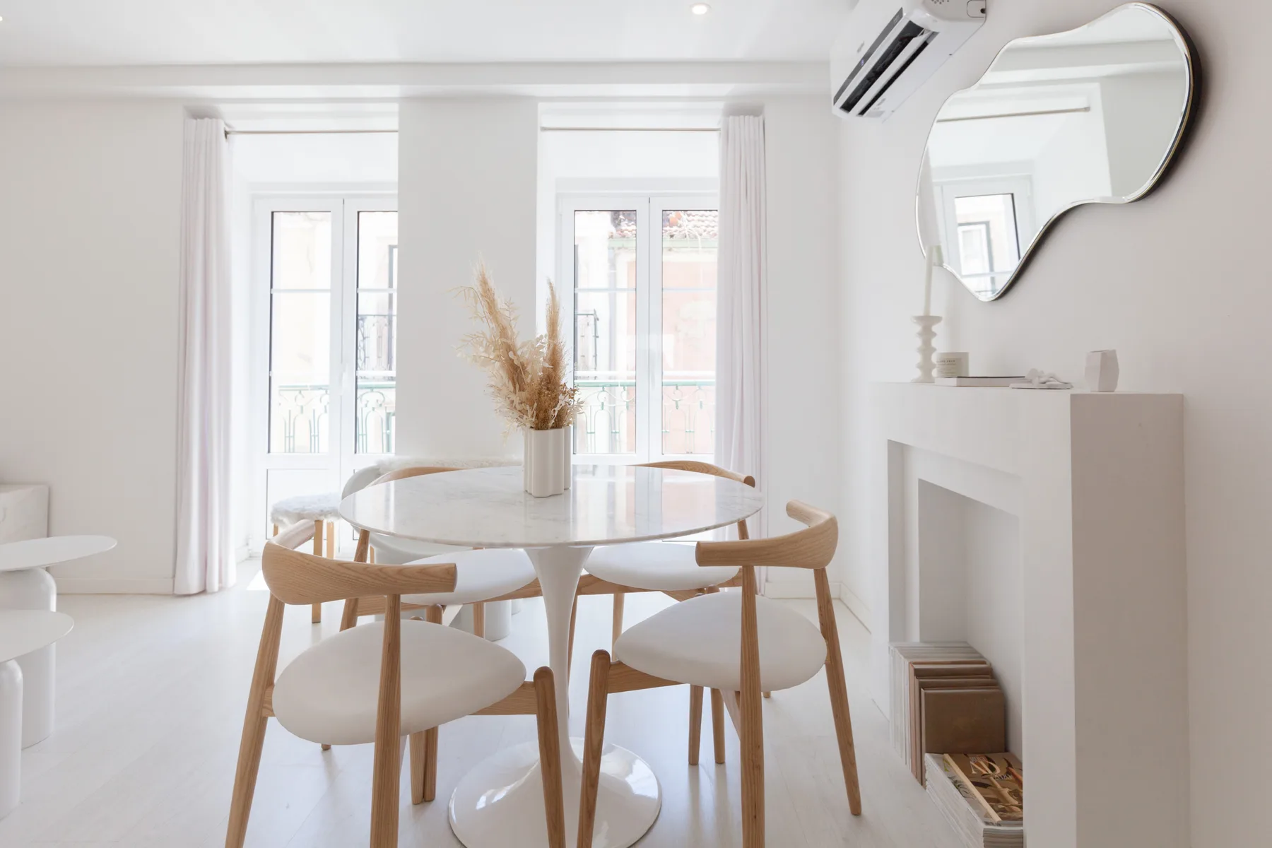Un comedor luminoso con una mesa redonda y sillas junto a ventanas altas.