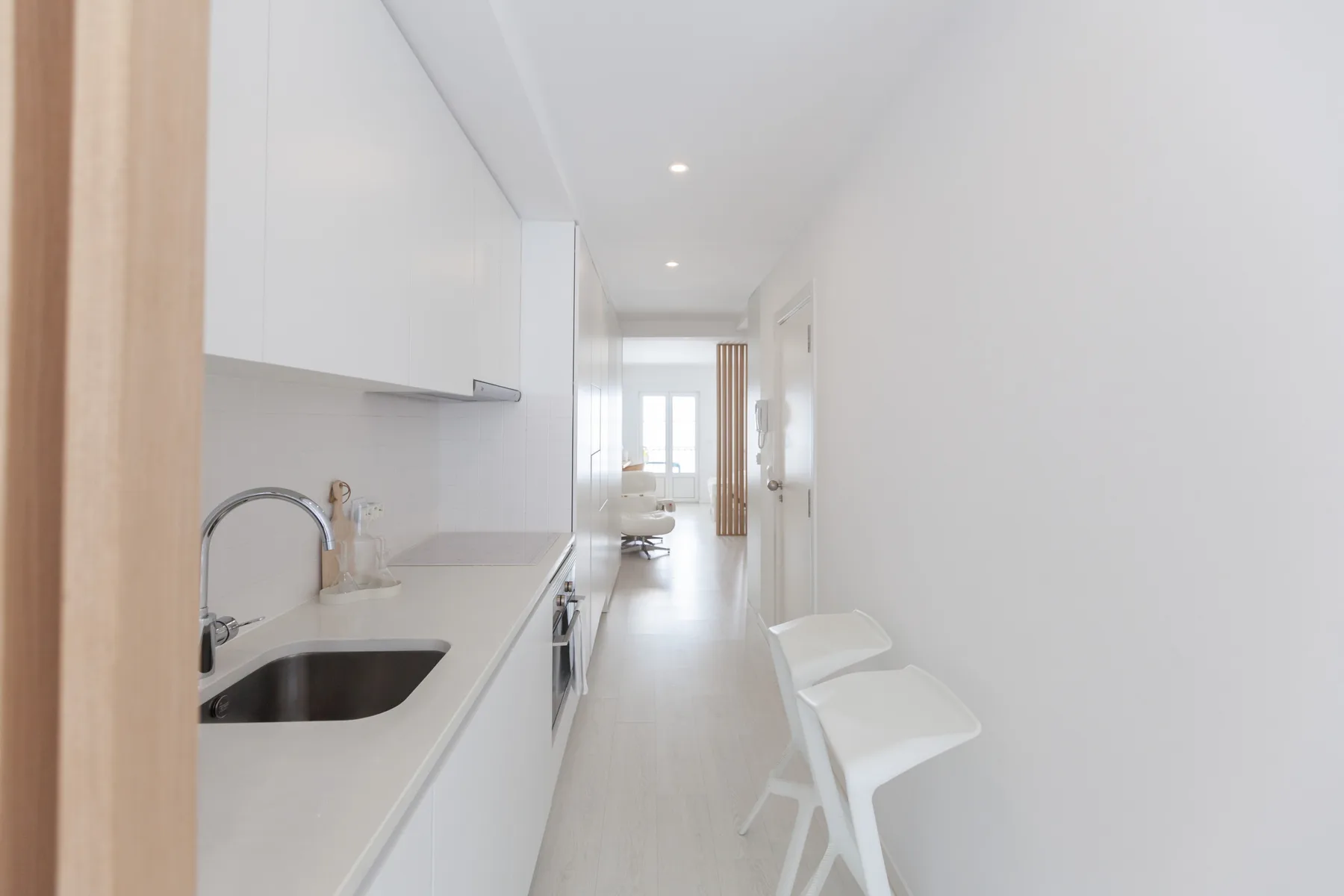 Una cocina luminosa con una encimera larga da a una estrecha zona de estar.