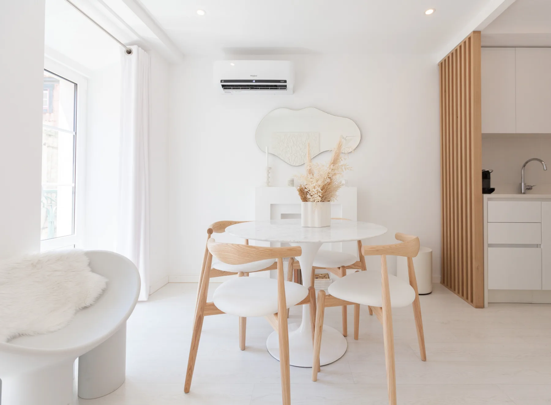 Un comedor luminoso con una mesa redonda y asientos claros junto a una ventana.