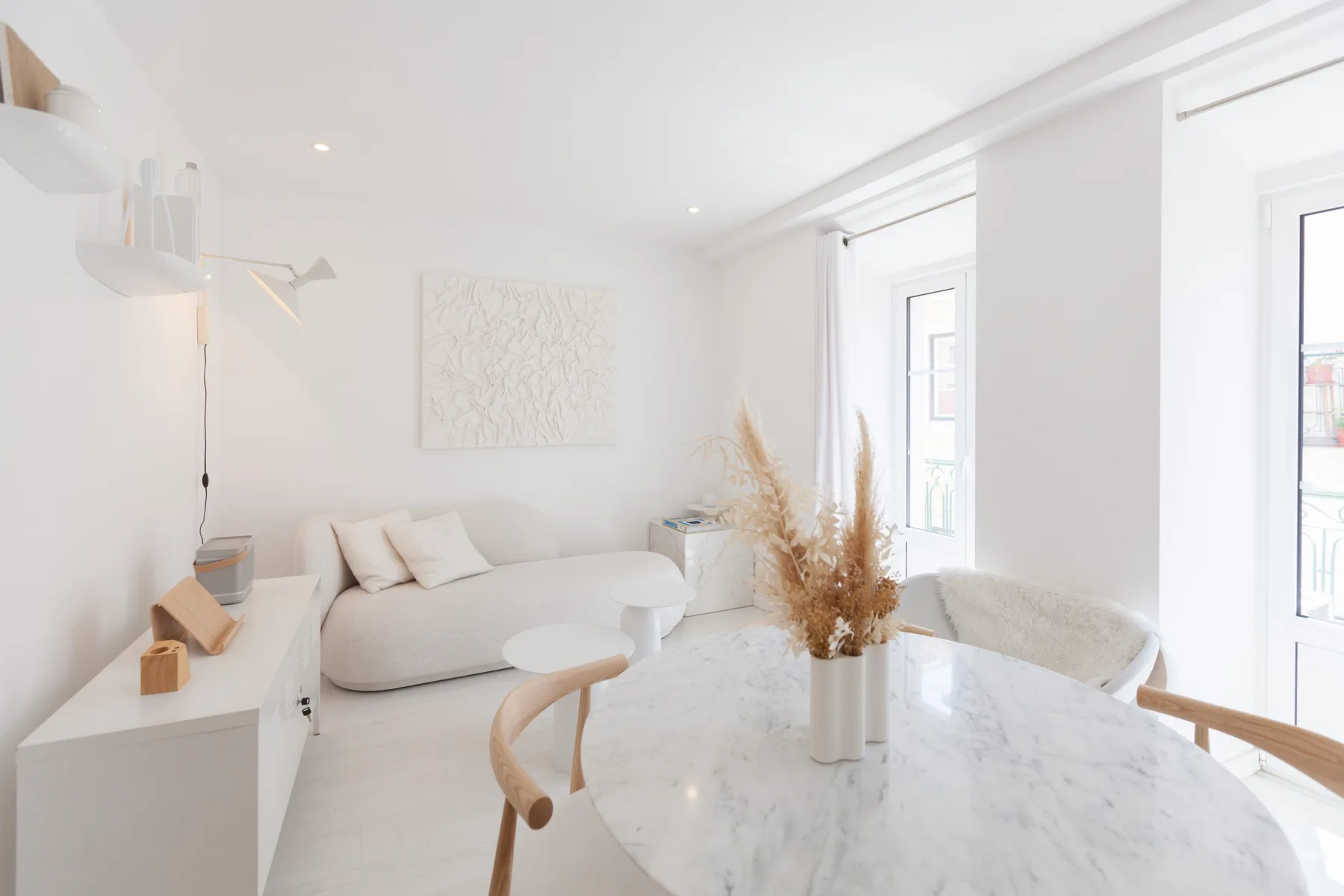 Una sala luminosa con un sofá, una mesa de centro y grandes ventanas.
