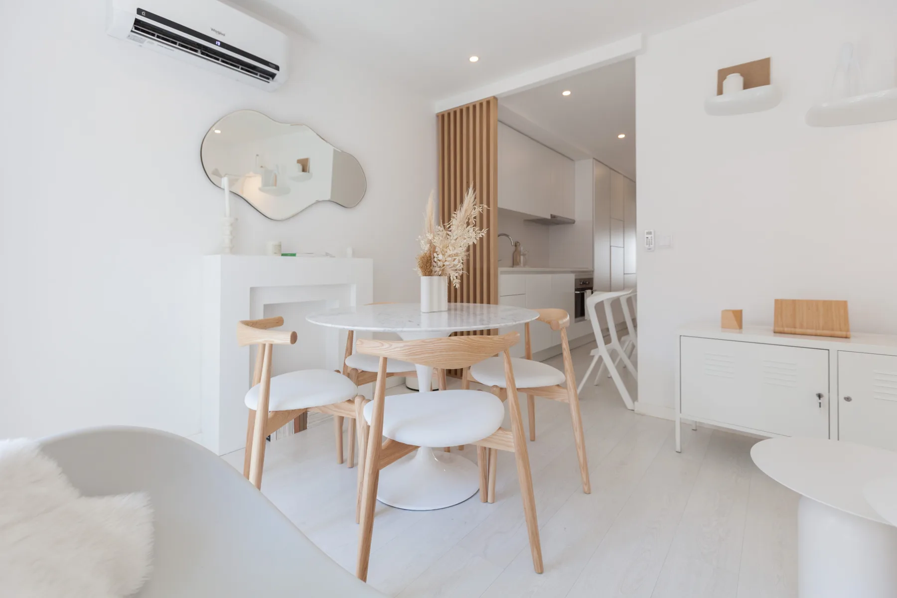 Un comedor luminoso con una mesa redonda y asientos de madera clara.