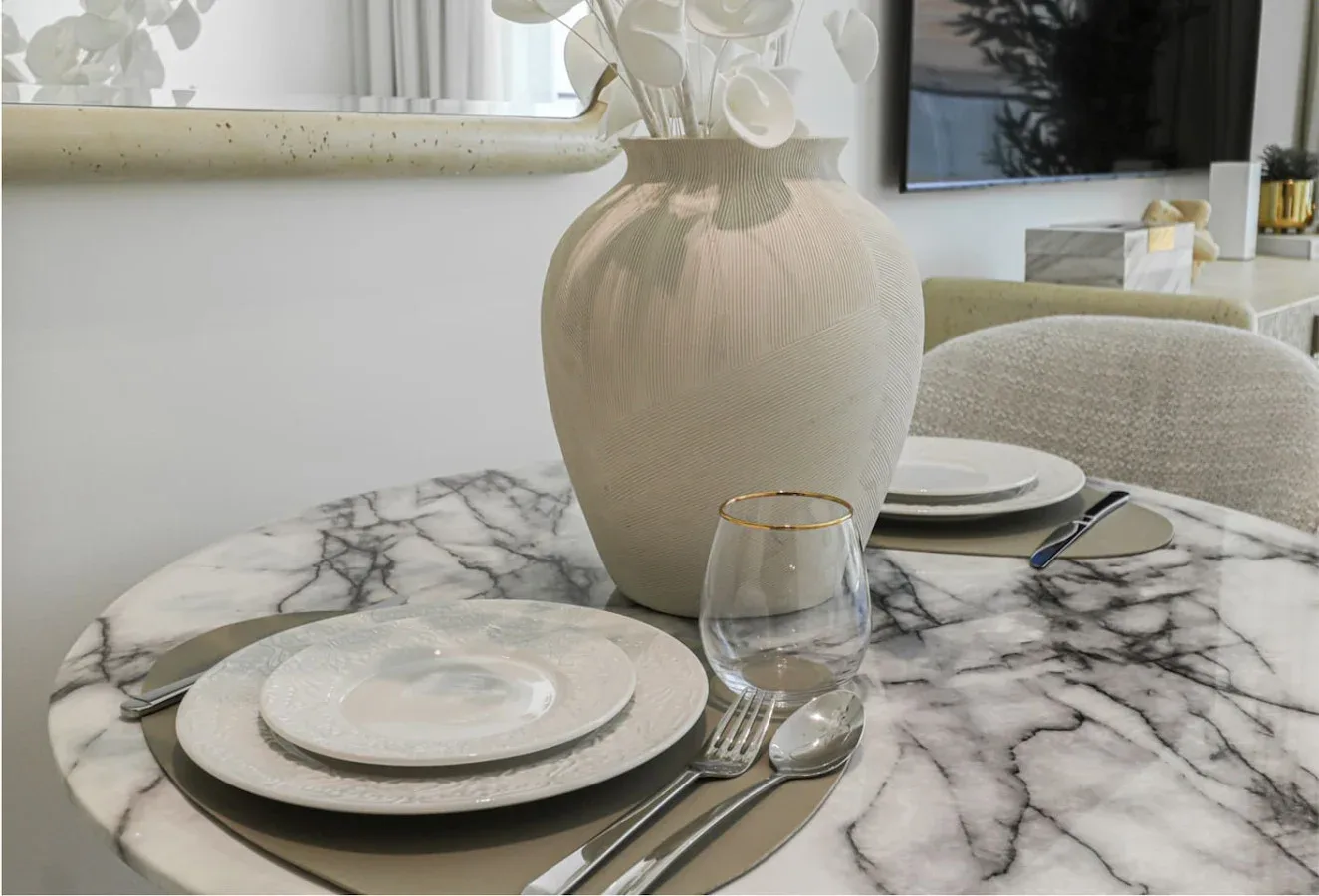 A dining table is set with plates, cutlery, and a vase.