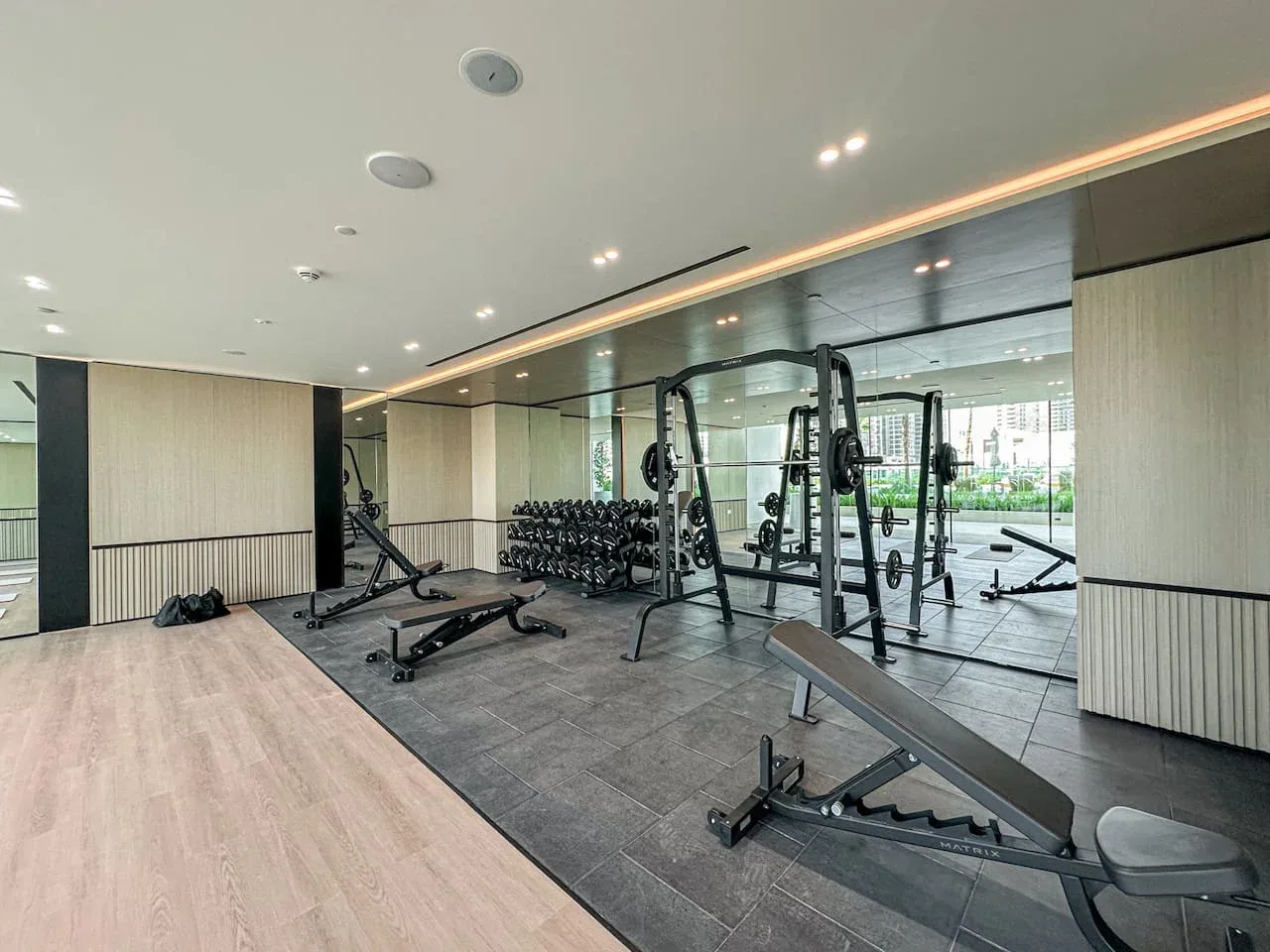 A gym with weight machines and workout benches beside mirrored walls.