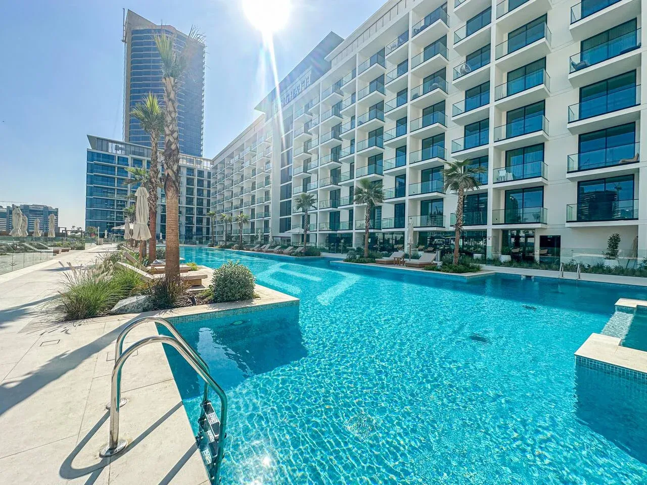 A swimming pool sits beside a modern multi-story building.