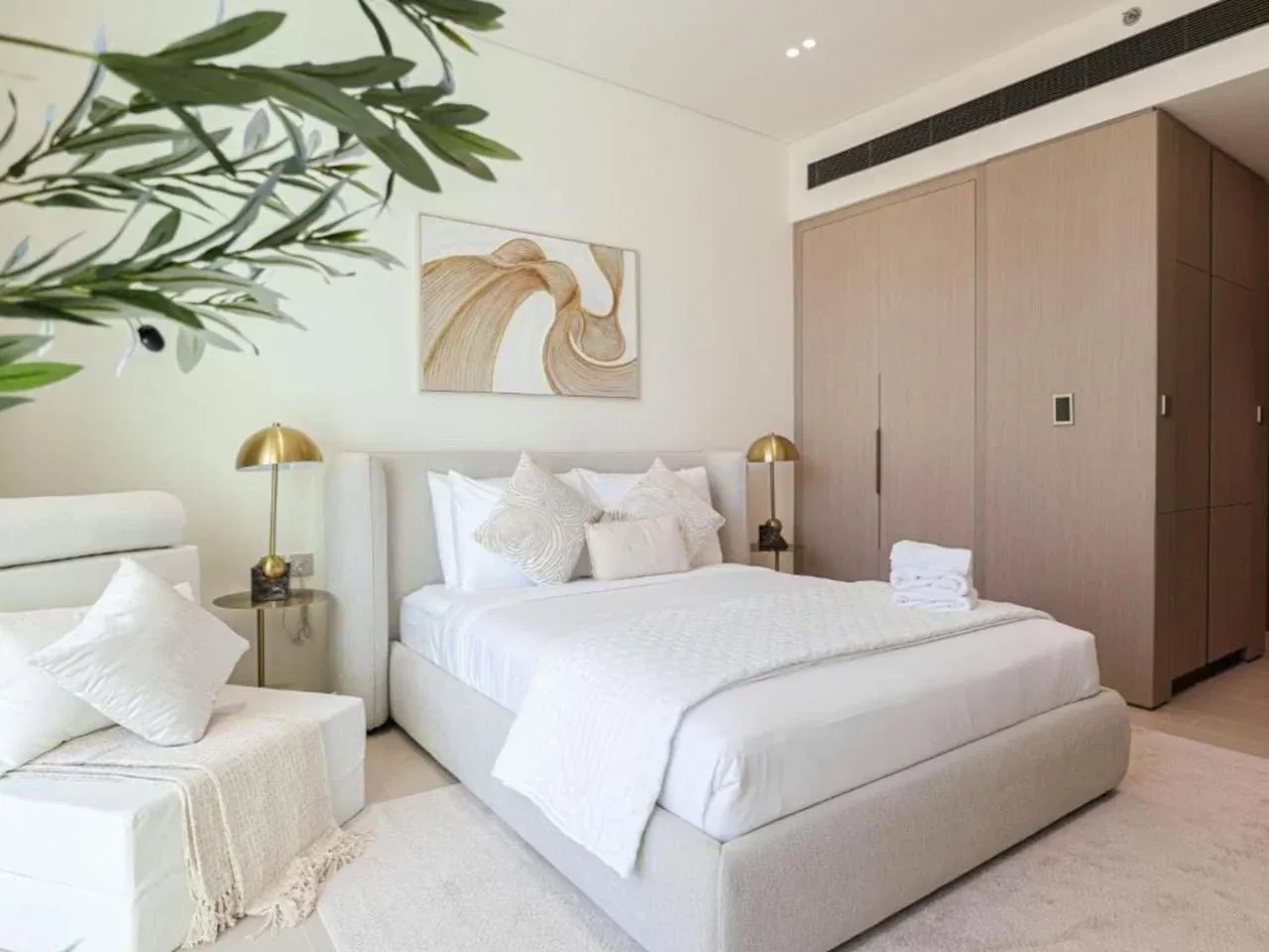 A bright bedroom with a neatly made bed and built-in wardrobes.