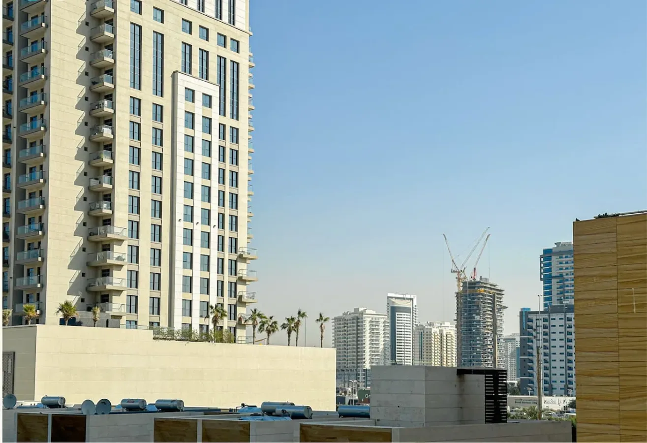 A cityscape with tall residential towers and high-rise buildings under a clear sky.