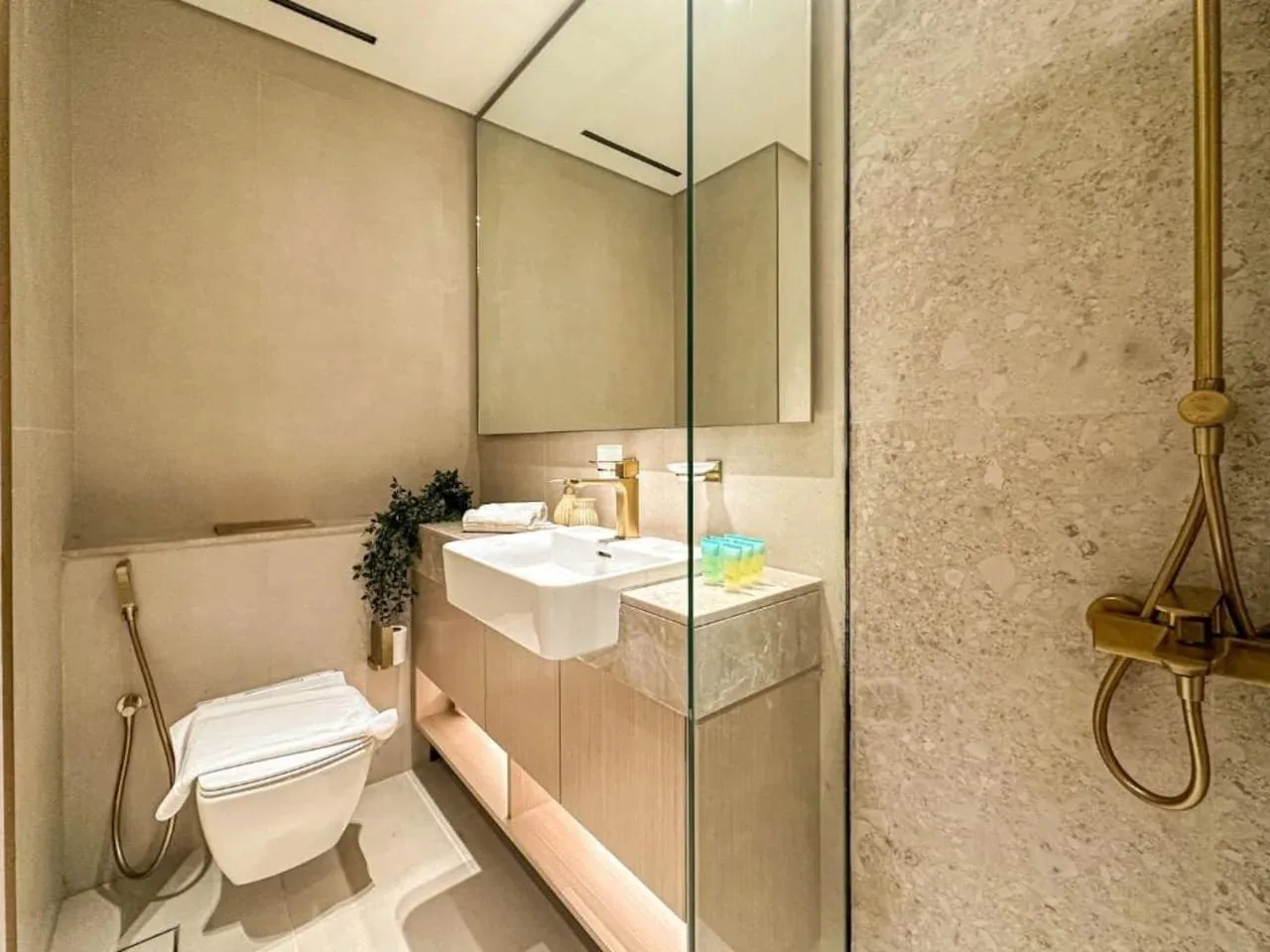 A modern bathroom with a vanity, toilet, and glass shower screen.