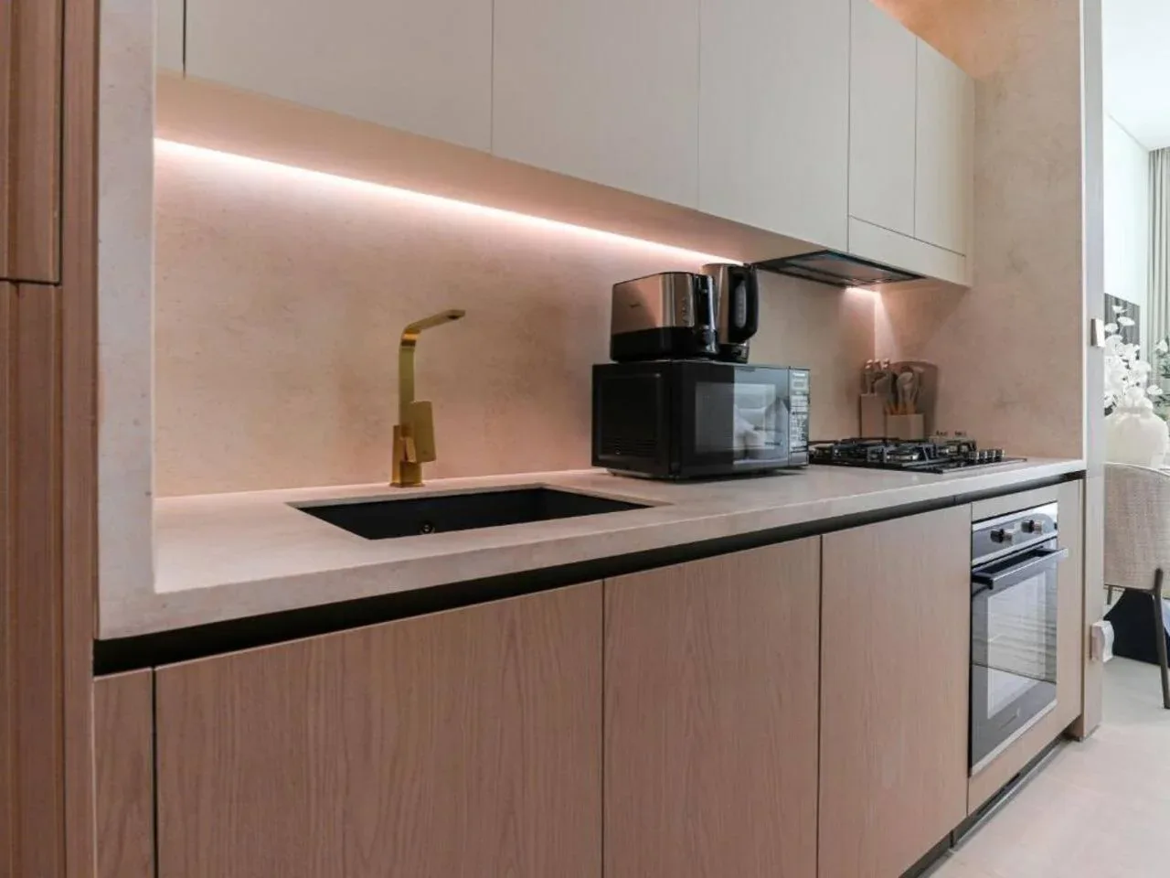 A modern kitchen with a long countertop, sink, and built-in appliances.