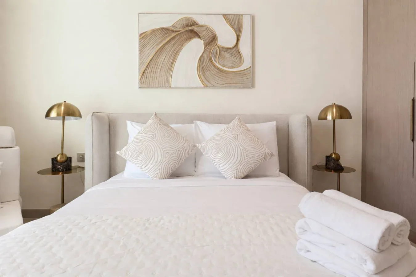 A neatly made bed with decorative pillows, bedside tables, and matching lamps.