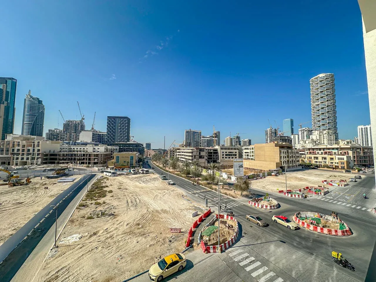 A city construction site and road intersection sit beneath a clear blue sky.