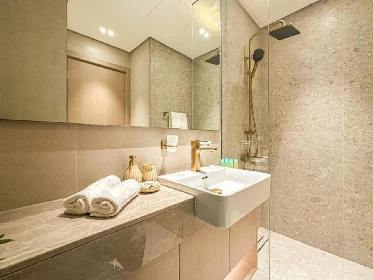 A bathroom with a wall-mounted sink, large mirror, and shower.