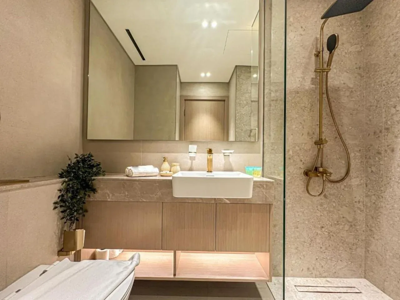 A modern bathroom vanity with a large mirror and a glass shower.