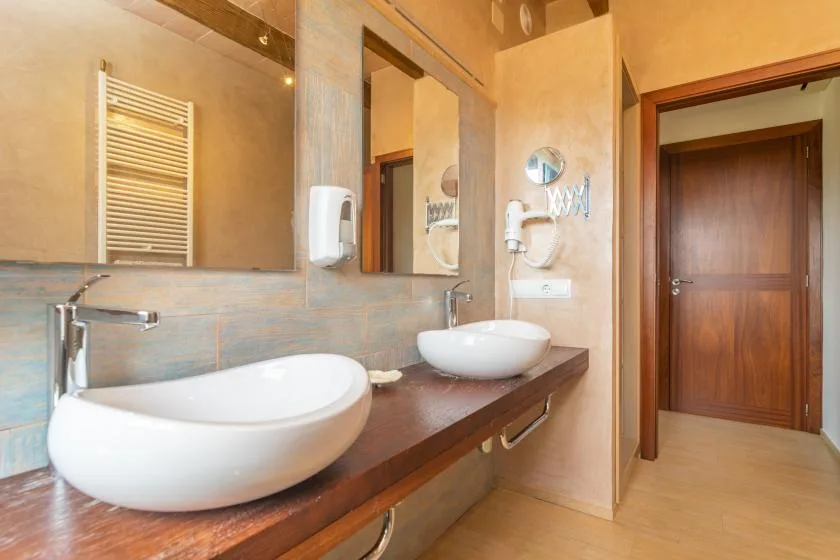 Un lavabo de baño con dos lavamanos, espejos y un toallero calefactable.