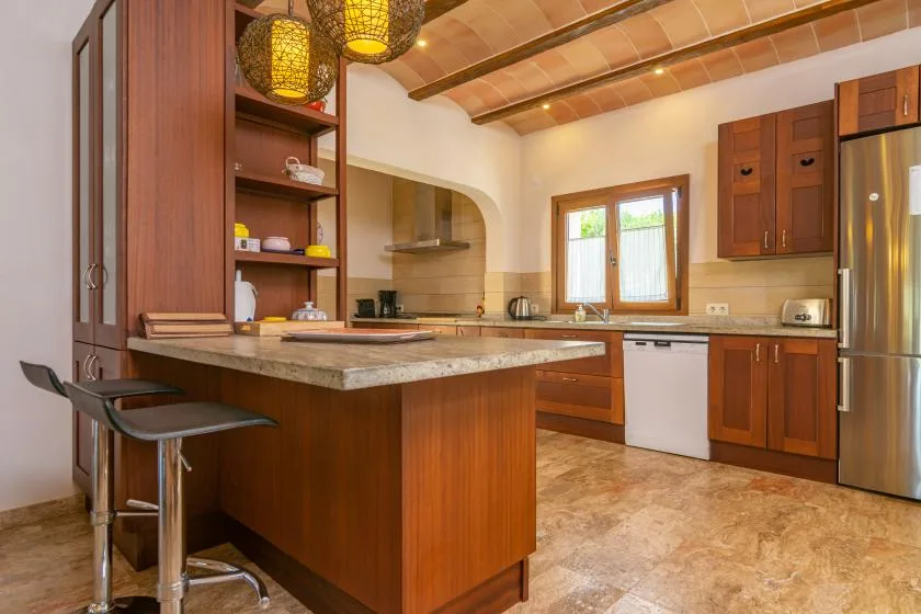 Una cocina amplia con armarios de madera, una isla central y una ventana.