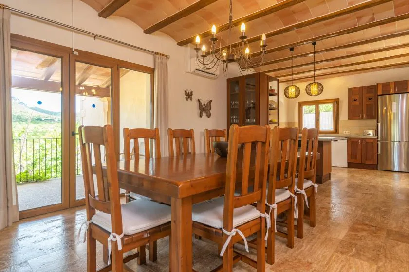 Comedor con una mesa larga de madera y sillas junto a puertas de vidrio.
