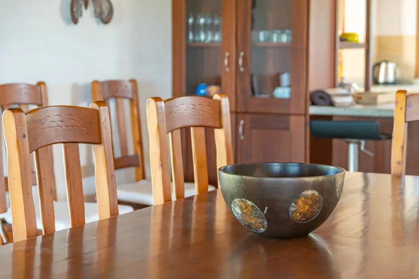 Un comedor con una mesa de madera, sillas y un cuenco decorativo.