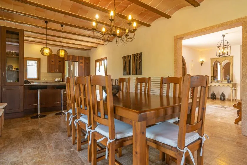 Comedor con una larga mesa de madera y sillas bajo vigas expuestas.