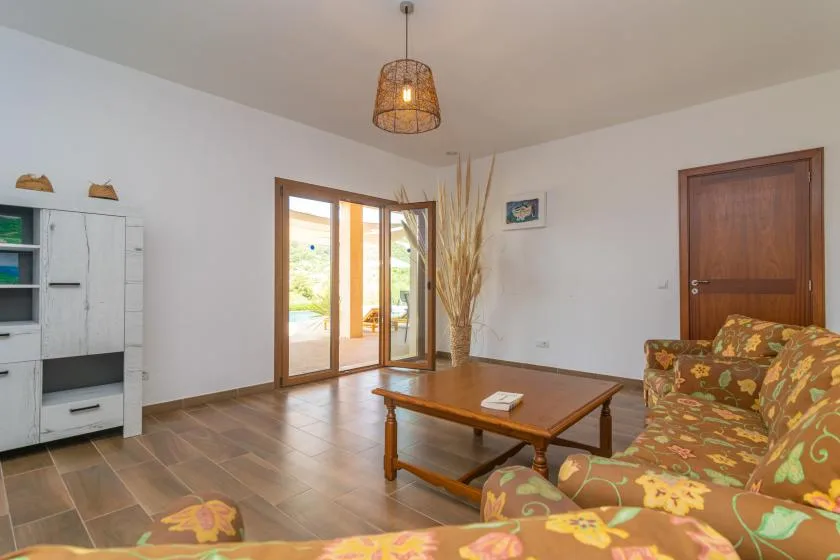 Una sala de estar con asientos estampados y una mesa de centro de madera junto a puertas de vidrio.