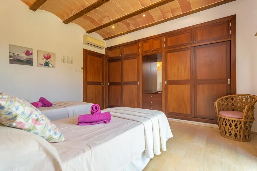 Un dormitorio con camas, armarios empotrados de madera y techo con vigas expuestas.