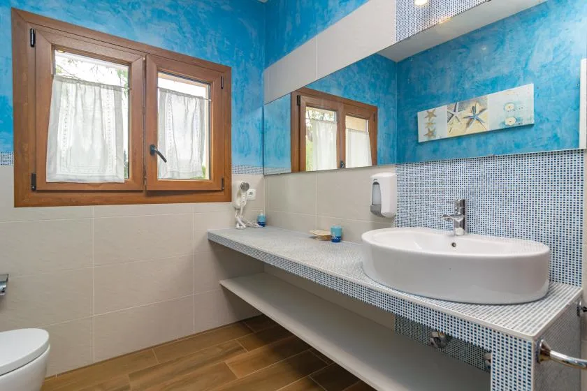 Un baño con una encimera larga con lavabo y una ventana enmarcada en madera.