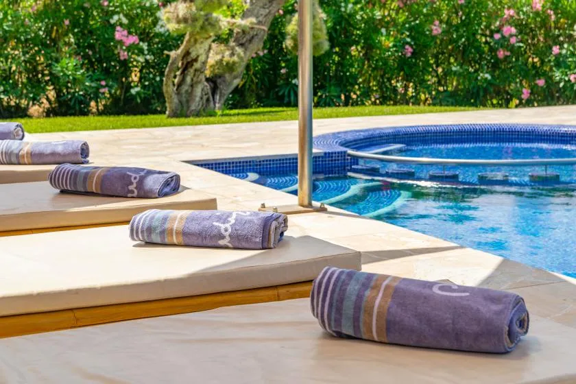 Tumbonas junto a la piscina tienen toallas dobladas.