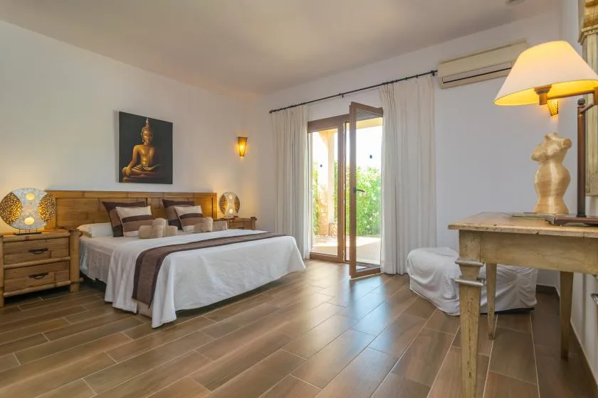 Un dormitorio con una cama, mesitas de noche y puertas de vidrio que dan a un patio.
