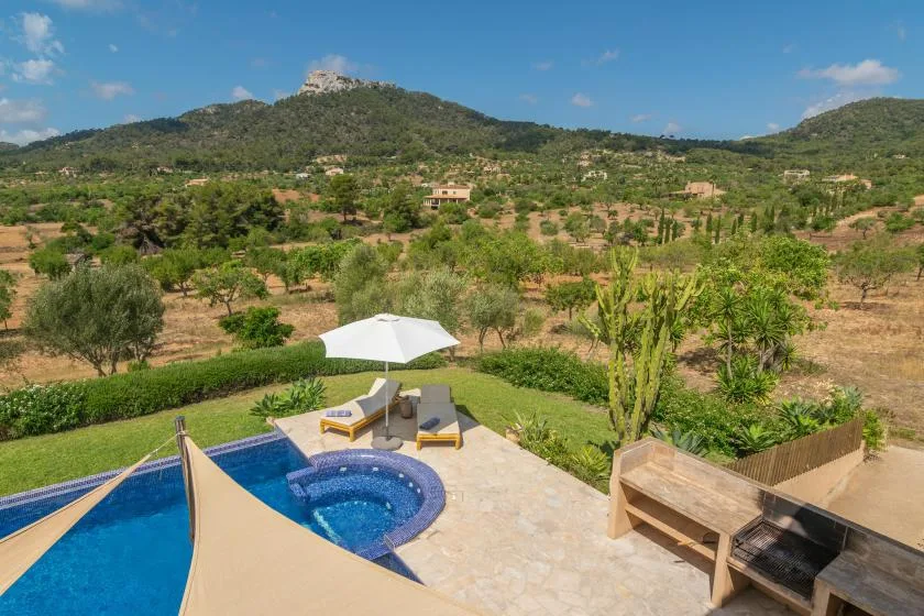 Una piscina y un patio ofrecen vistas a un paisaje verde y montañoso.