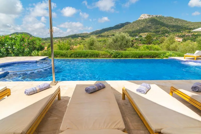 Una piscina tiene vistas a colinas verdes, con tumbonas junto a la piscina.