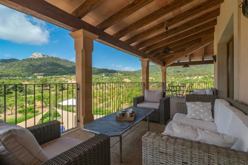 Una terraza cubierta con asientos al aire libre da a un valle verde.