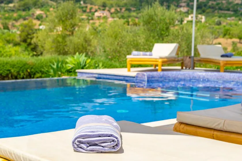 Una piscina con asientos de descanso y una toalla doblada en la terraza.