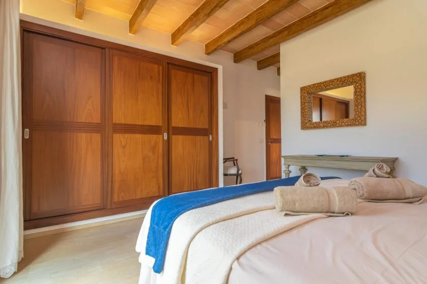 Un dormitorio con una cama, un armario de madera y vigas a la vista.