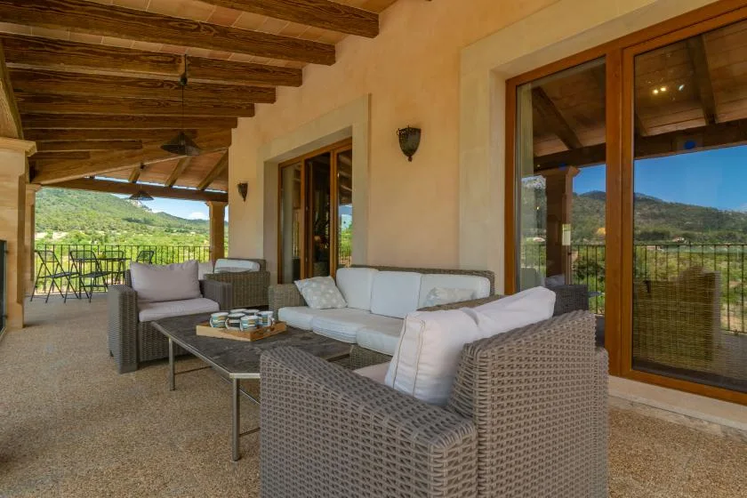 Un patio cubierto con asientos tejidos y vistas de colinas verdes.