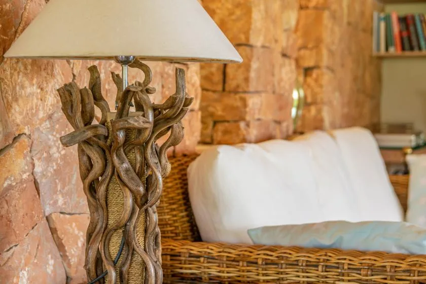 Una zona de descanso con asiento tejido, cojines blancos y una lámpara escultural.