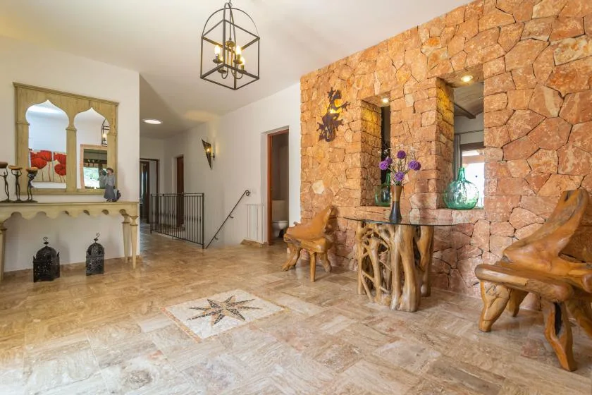 Una sala con paredes de piedra cuenta con asientos de madera y una chimenea decorativa.