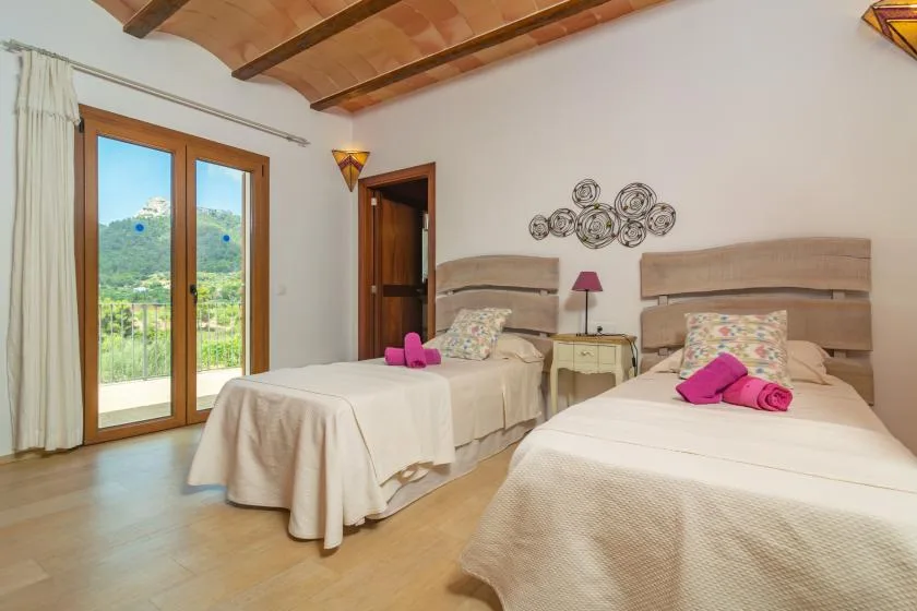 Un dormitorio con dos camas, una mesita de noche y puertas de vidrio que dan a un balcón.
