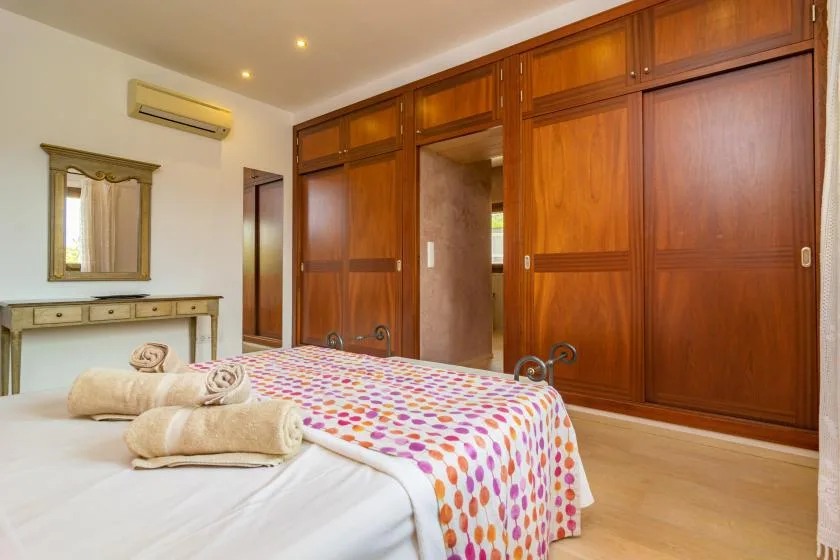 Un dormitorio con una cama cubierta por una colcha estampada de colores y armarios de madera.