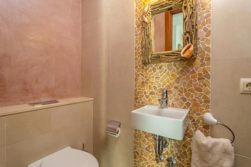 Un baño con un lavabo de pared y una pared de mosaico.