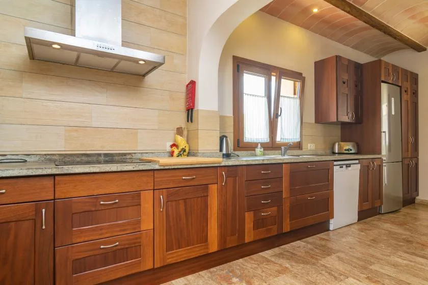 Una cocina amueblada con armarios de madera, una encimera y una ventana.