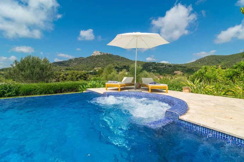 Una piscina con agua burbujeante y tumbonas está junto a una terraza soleada.